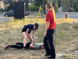 Gendarme Jessica Scott supervisant les jeunes qui essaient le menottage lors d’une formation par scénario