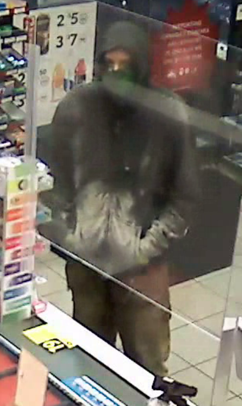 Photo of male suspect described as being 6 feet tall, with a slender build, wearing a dark-coloured hoodie with what appears to be white spatter on the front, beige work pants, tan work boots, work gloves and a green mask.